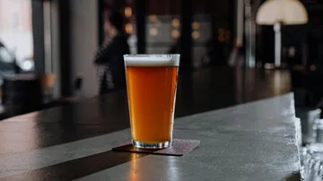 Ein Glas Bier steht auf einer Bartheke in einem Pub.