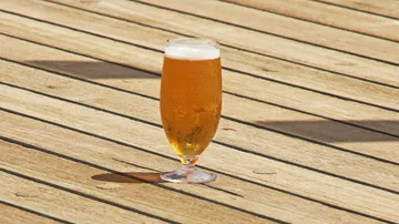 Ein Glas Bier steht auf einem Holzboden.