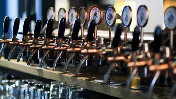 Taps dispense beer in a bar with glasses.