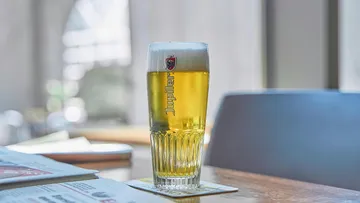 A beer glass is standing on a table and waiting.