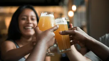 Glasses of beer are raised in a happy group.