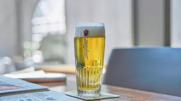 A beer glass is on a table in a bar.