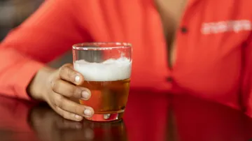 Ein Glas Bier wird von einer Hand gehalten.