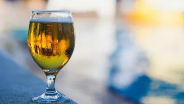 Ein Glas Bier steht am Rand eines Beckens.