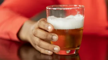 Ein Glas Bier wird von einer Hand gehalten.