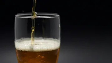Ein Glas wird mit einem goldenen Getränk gefüllt.