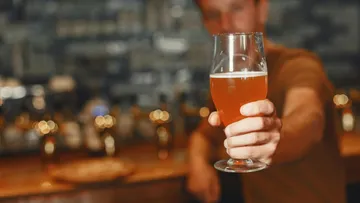 Ein Mann hält ein Bierglas in einer Bar.