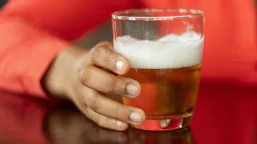 Ein Glas Bier wird von einer Hand gehalten.