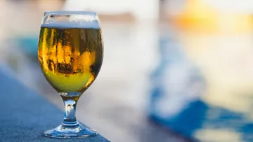 A glass of beer is standing on the edge, surrounded by water.