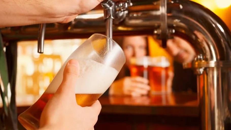 A glass is filled with beer while guests watch.