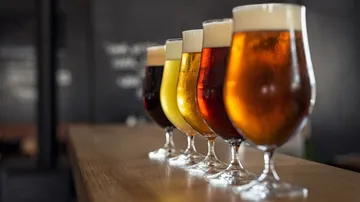 Sechs Biergläser stehen nebeneinander auf einem Tisch.