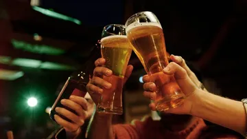 Gläser stoßen an, während Menschen in einer Bar feiern.