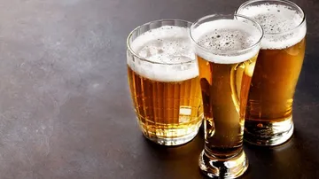 Drei Gläser Bier stehen auf einer dunklen Oberfläche.