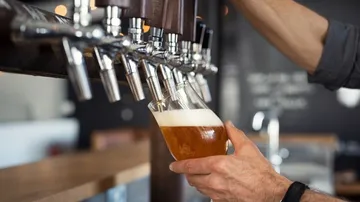Ein Glas wird mit Bier am Zapfhahn gefüllt.