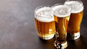 Drei Gläser Bier stehen auf einer dunklen Fläche.