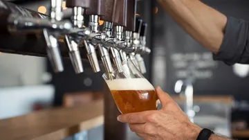 Glass is filled at the tap for beer. Bar atmosphere.
