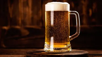 Ein Bierglas steht auf einem Holzständer, schaumig.