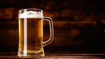 Ein Bierglas steht auf einem Holztisch, halb voll.