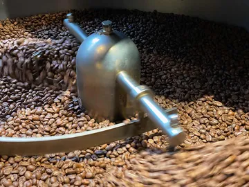 Kaffeebohnen werden in einem Röster gleichmäßig bewegt.