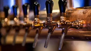 Copper taps fill a glass with beer.