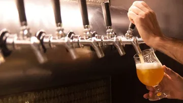 Zapfhahn schüttet Bier in ein Glas, Barumgebung.