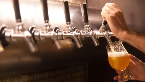 Ein Glas Bier wird aus einem Zapfhahn gezapft.