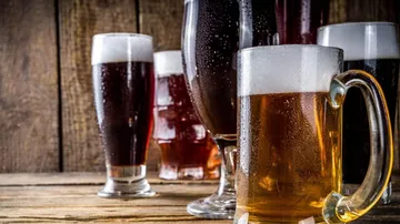 Mehrere Biergläser stehen auf einem Holztisch.
