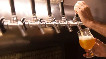 Glas wird mit Bier an Zapfanlage gefüllt.