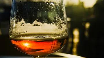 A glass with a drink shows drops and sunlight.