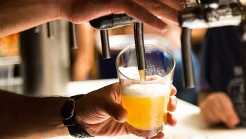 Glas wird mit Bier gefüllt, in einer Bar-Umgebung.