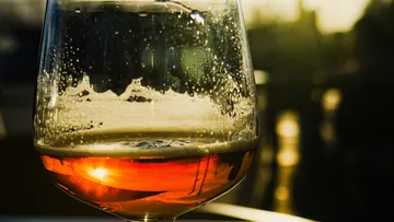 Ein Glas mit Getränk, feucht, im Sonnenlicht drapiert.