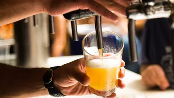 Glass with beer is filled from a tap.