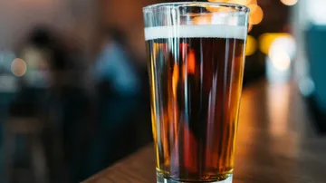 Ein Glas Bier steht auf einem Holztisch in der Bar.