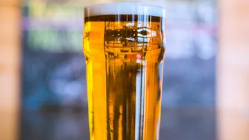 A beer glass is on a table in a bar.