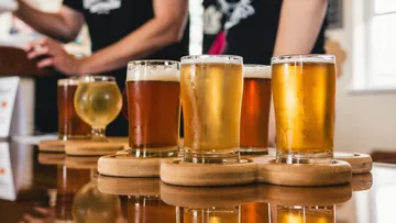 Beer glasses stand on a wooden board in a bar.