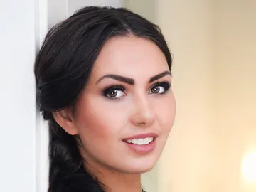 Woman smiles pleasantly against a blurred background.