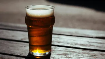 Ein Glas Bier steht auf einem Holztisch.