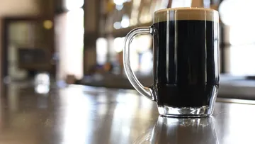 Black beer in a glass on a counter.