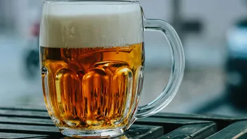 A glass of beer is sitting on a table in the sun.