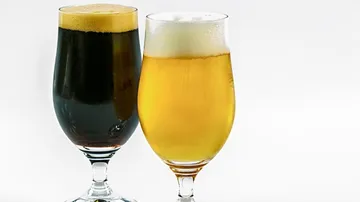 Zwei Gläser Bier stehen nebeneinander, dunkles und helles.