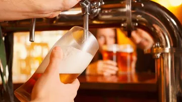 Ein Glas wird mit Bier an einem Zapfhahn gefüllt.