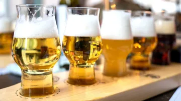 Four beer glasses are placed on a wooden board.
