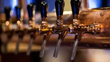 Glänzende Zapfhähne schenken Bier in einer Bar.