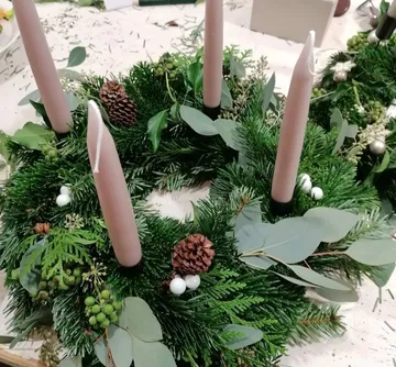 Grüner Adventskranz mit vier Kerzen und Naturdekoration.