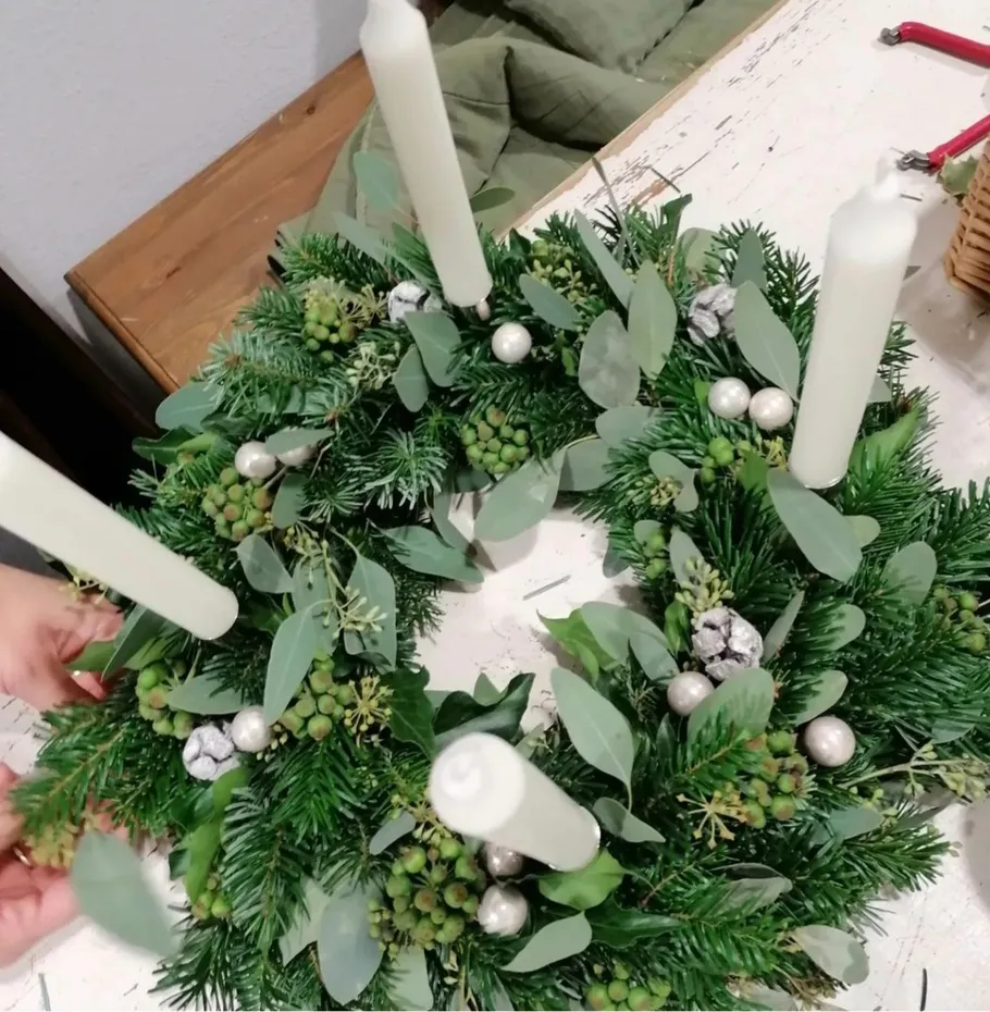 Green advent wreath with white candles is decorated.