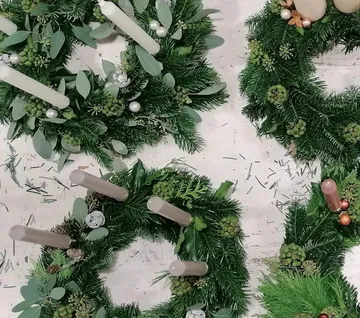 Drei Adventskränze mit Kerzen und grünem Tannenzweigen.