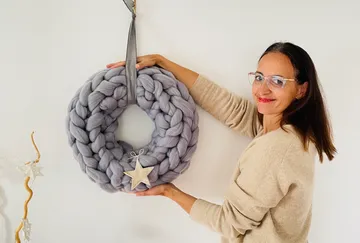 Woman holding a gray braided wreath with a star.