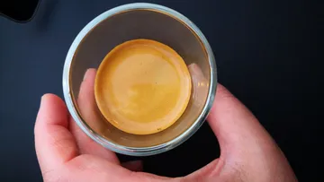A glass of coffee is held by one hand.