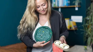 Woman holding colored plates and smiling in a room.