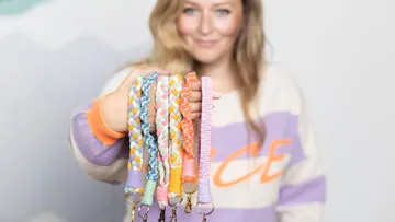 Colourful braided keychains are held by one person.